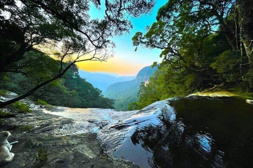 Un río serpentea por un valle boscoso con una cascada y terreno rocoso. 5