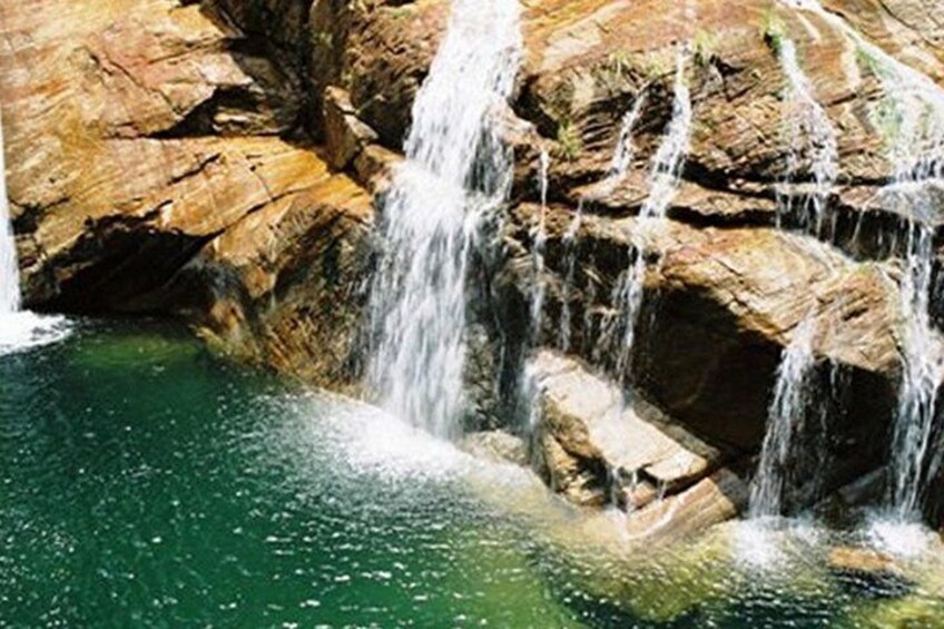 Una cascada se precipita sobre rocas hacia una piscina de agua cristalina. 4