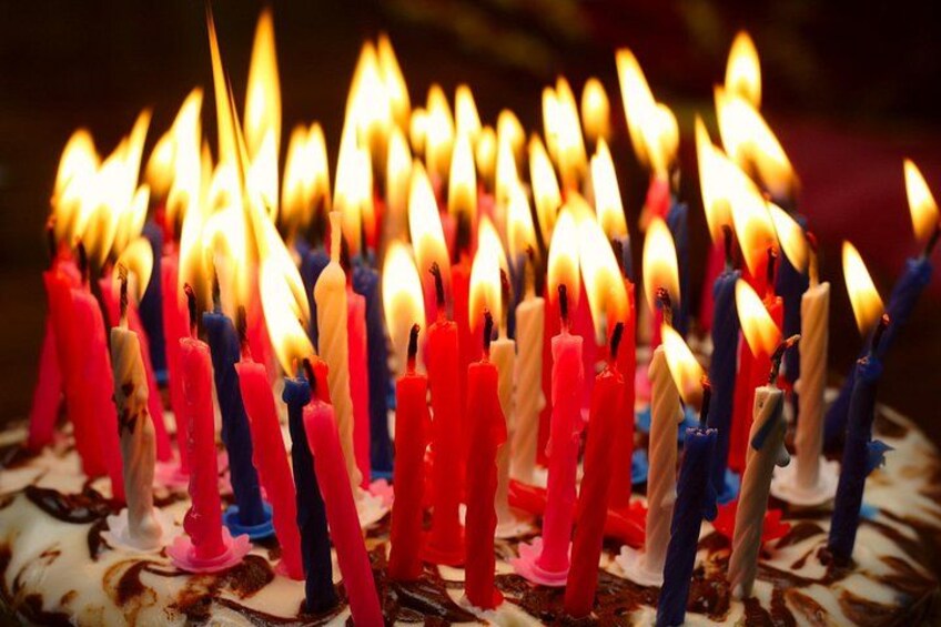 A cake with lit candles in various colors. 1