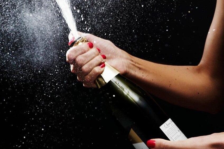 A hand holding a champagne bottle, with champagne being sprayed out. 2