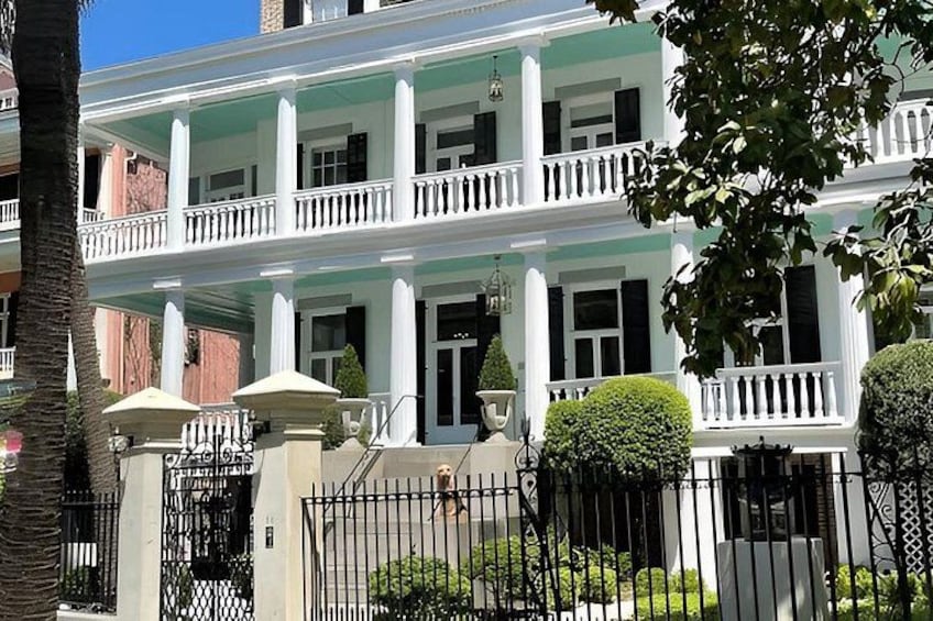 A two-story building with a white facade, columns, and a balcony. 2