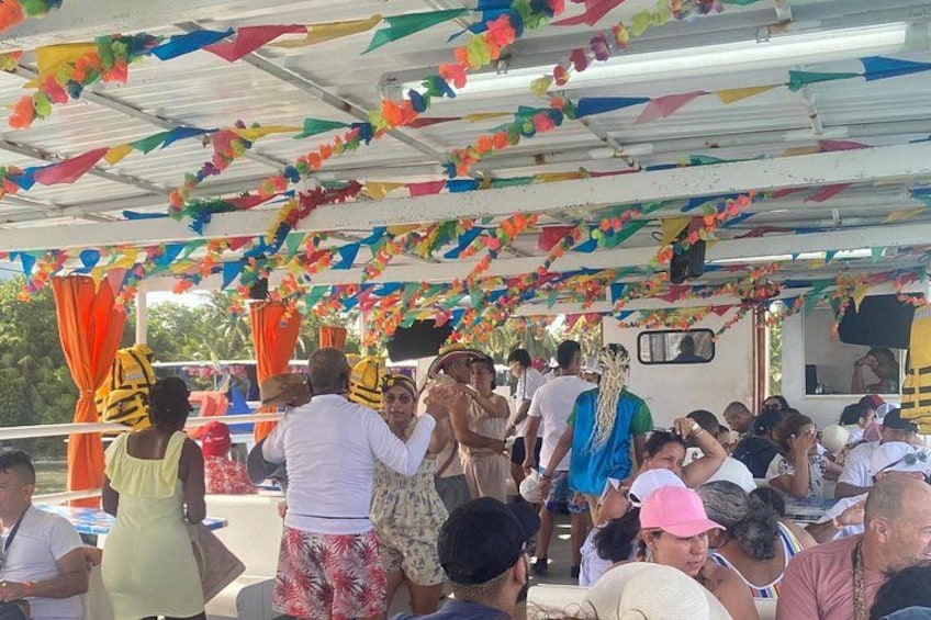 A covered outdoor gathering with people, a boat, and colorful decorations. 1