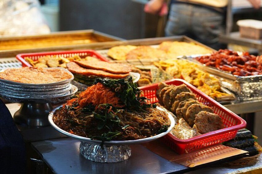 Un'ampia scelta di piatti su un tavolo a buffet, tra cui una grande insalatiera, diversi vassoi di carne e un cestino di pane. 3