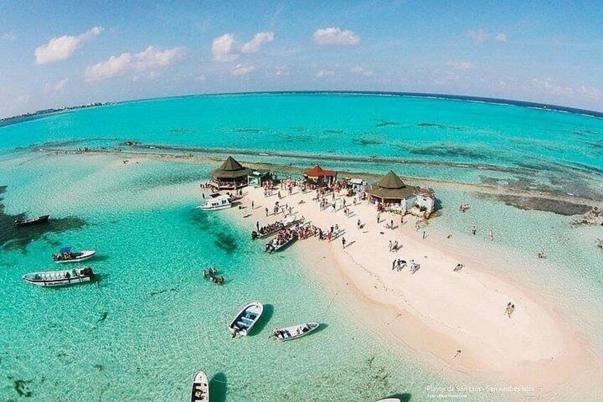 Une plage à l’eau turquoise et limpide, un rivage sablonneux et plusieurs bateaux. 5
