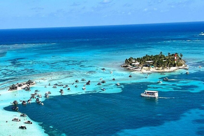 Une île tropicale aux eaux turquoise et limpides, un petit bateau et un phare. 1