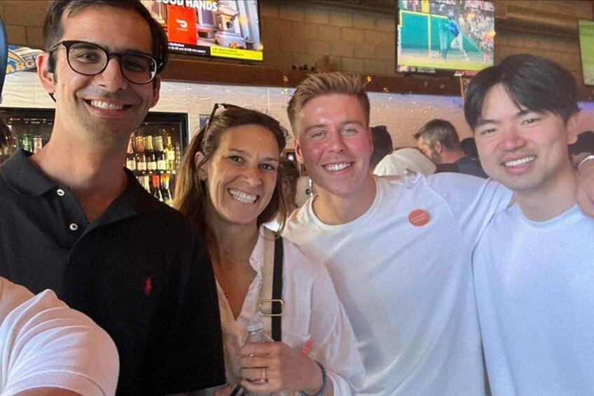 A group of people in a bar setting with a television screen in the background. 2