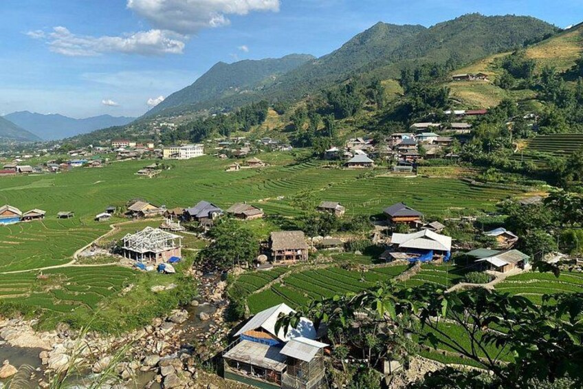 A rural village with terraced fields, houses, and mountains in the background. 2