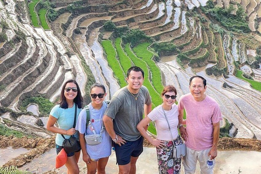 A group of people standing in front of terraced rice fields. 5