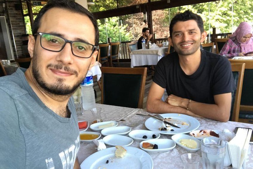 Dos personas sentadas a una mesa con platos de comida, una botella de agua y un vaso. 1