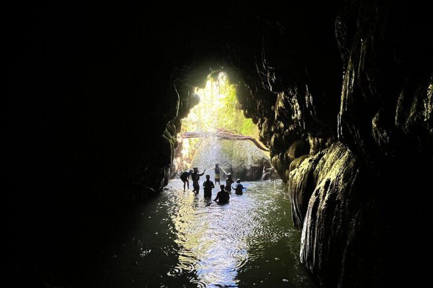 A group of people in a cave with water, illuminated by natural light. 2