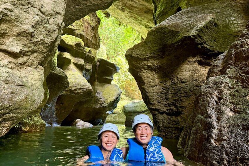 Two people in a cave with water flowing through it. 1