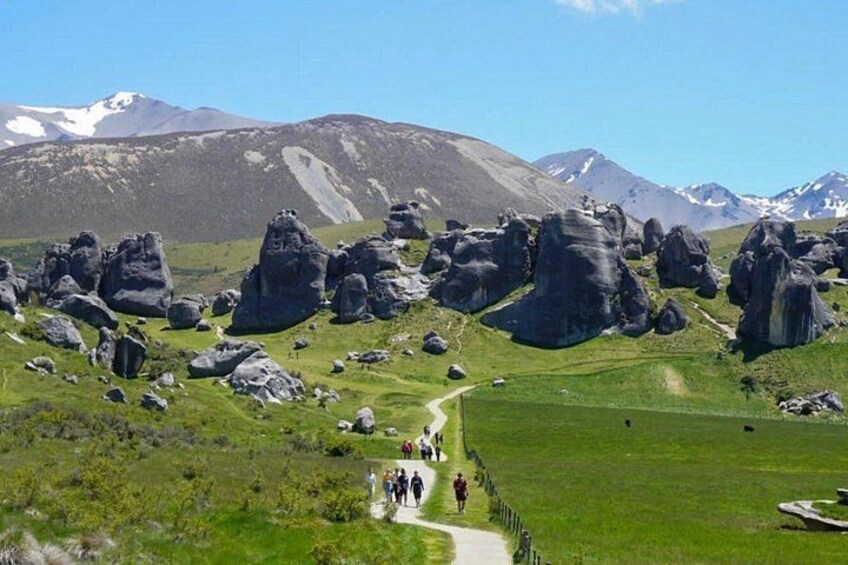 A mountainous landscape with large rock formations and a group of people walking on a path. 5