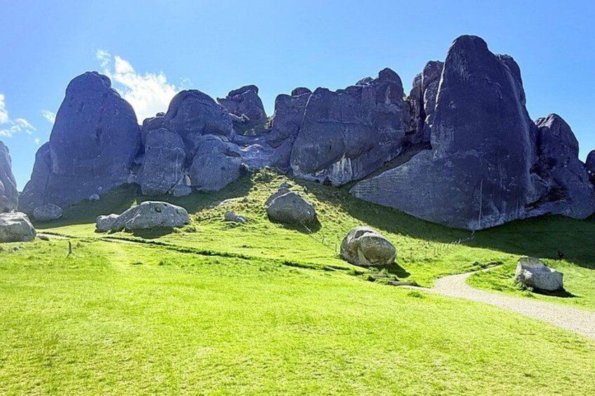 A grassy landscape with large boulders and a clear sky. 2