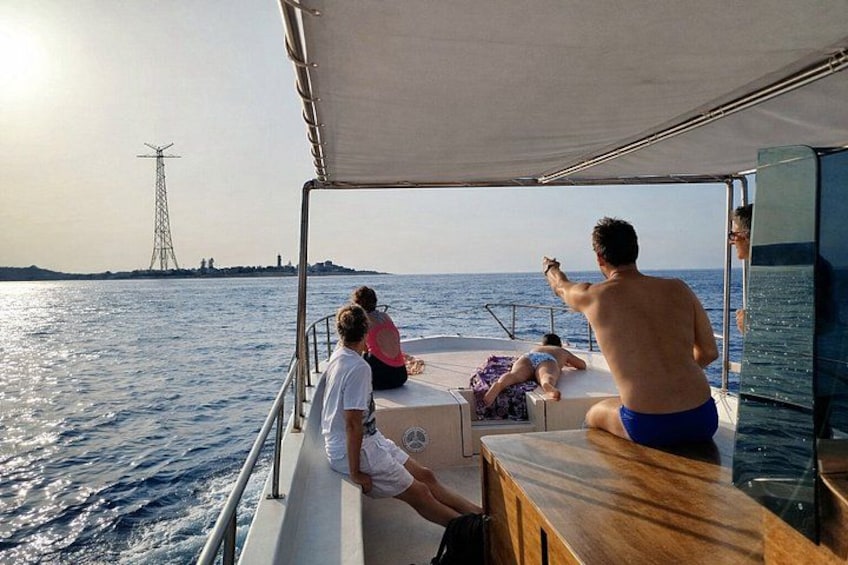 A boat with people on deck, a person pointing towards the horizon, and a distant power line tower. 2