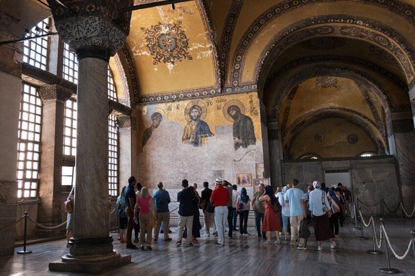 Interior de un edificio histórico con un grupo de personas mirando un mosaico. 2