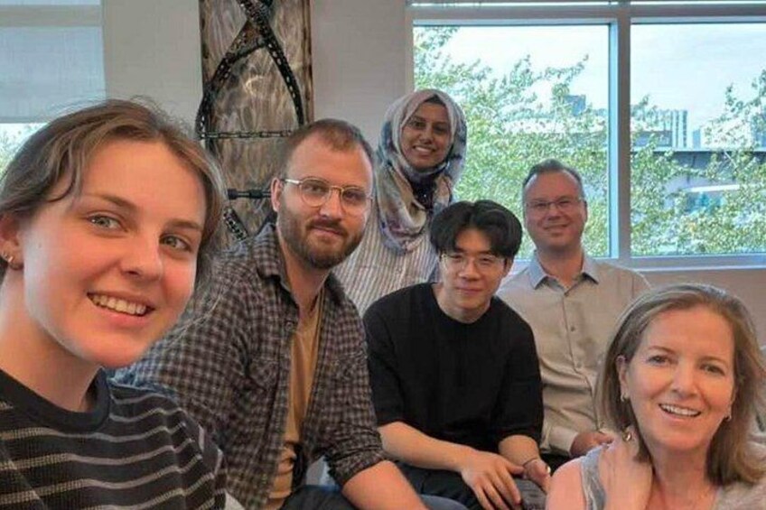 En grupp människor sitter inomhus med ett fönster i bakgrunden. 2