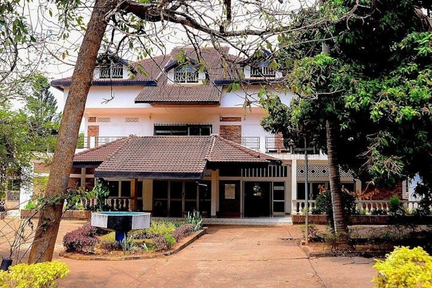A two-story house with a tiled roof, surrounded by trees and a garden. 2