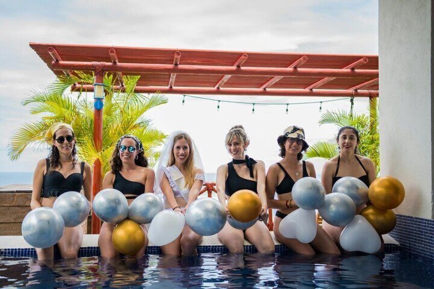 A group of people sitting in a pool with balloons. 3