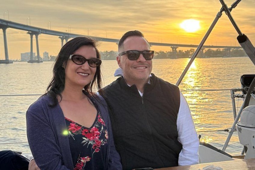 Two people on a boat with a bridge in the background. 2
