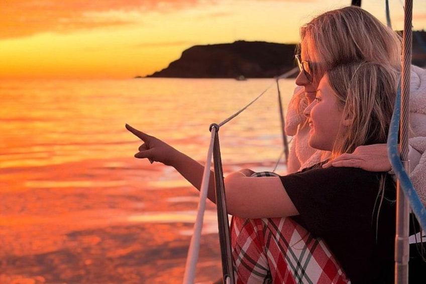 A person pointing towards a sunset over the ocean. 1