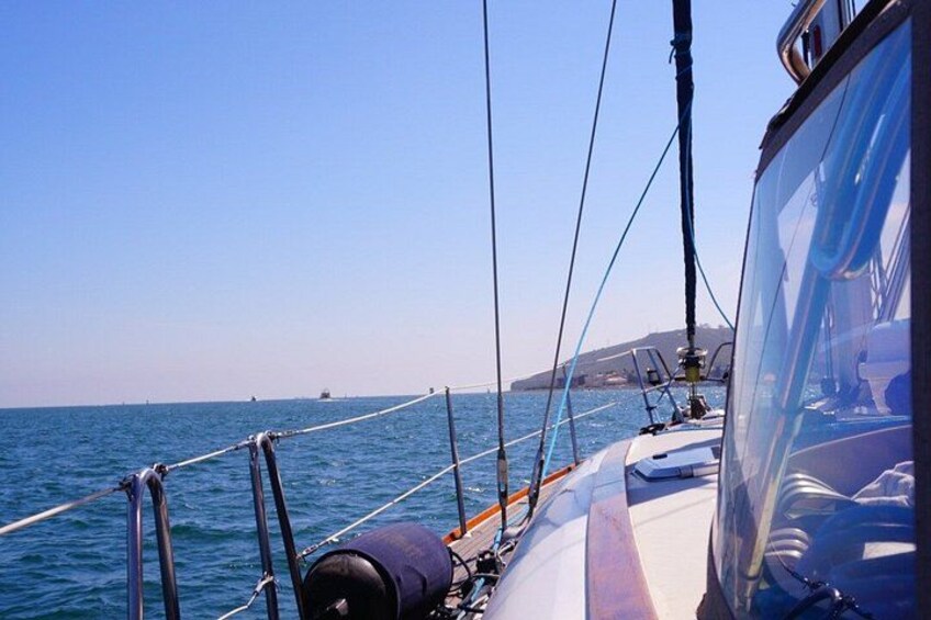 A sailboat on the water with a clear sky and distant land. 2