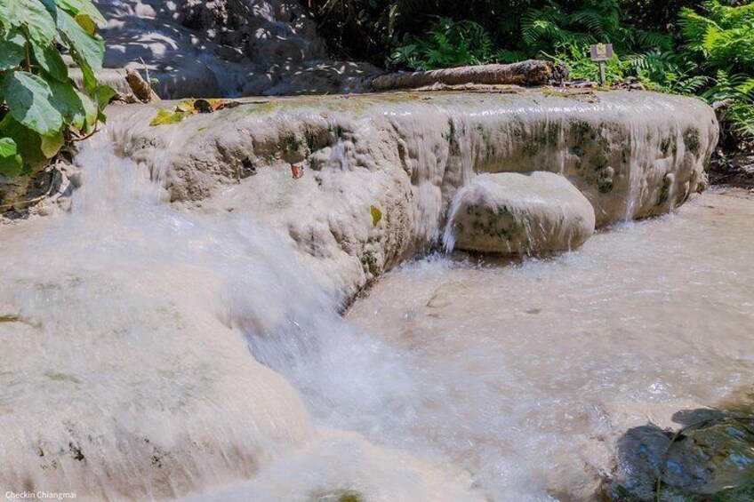 A natural water feature with a small waterfall, surrounded by rocks and greenery. 5
