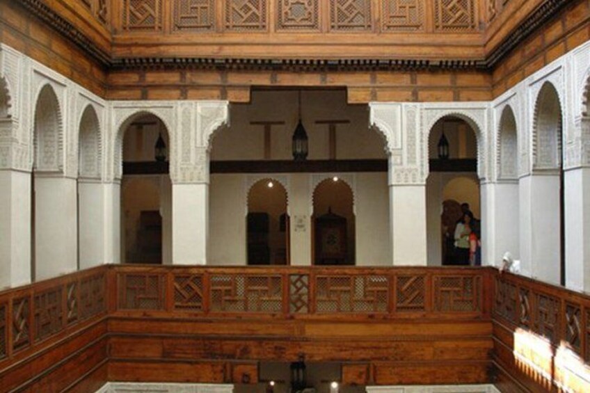 An interior courtyard with wooden benches, arches, and intricate wall designs. 2