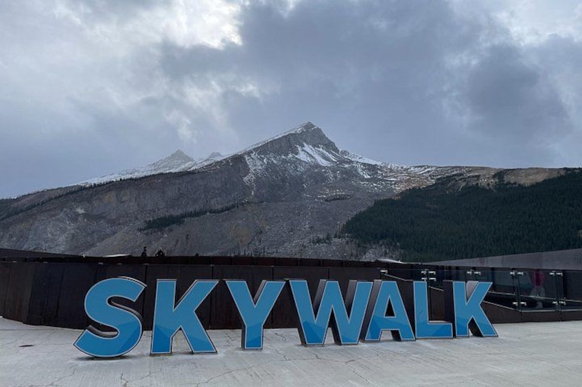 Een groot bord met de tekst 'SKYWALK' voor een berg. 3