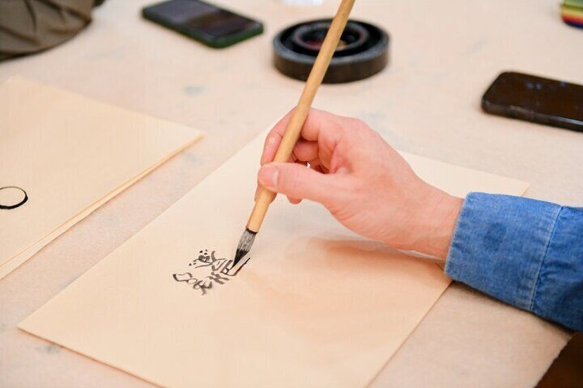 A person writing calligraphy on a piece of paper with a brush. 1