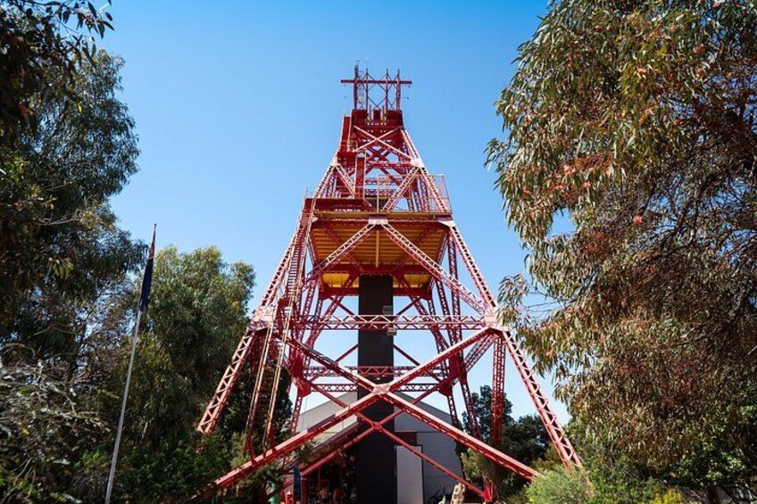 A red metal structure with a cross at the top, surrounded by trees. 5