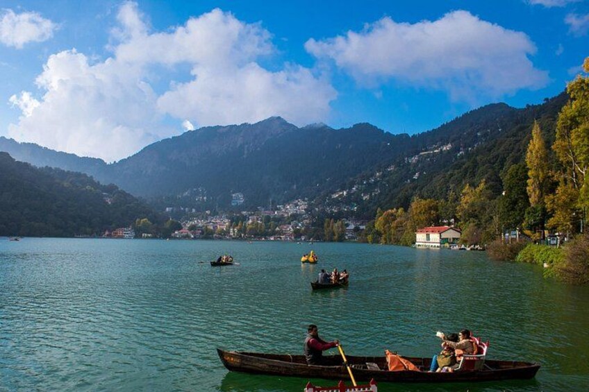 A calm lake with boats, mountains, and a small town in the background. 4