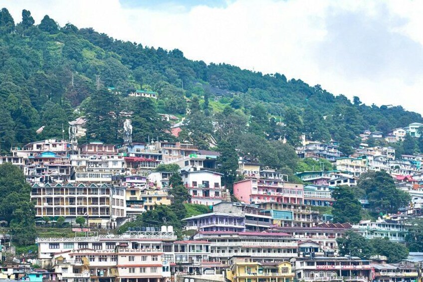A densely packed hillside town with colorful buildings and lush green hills in the background. 3