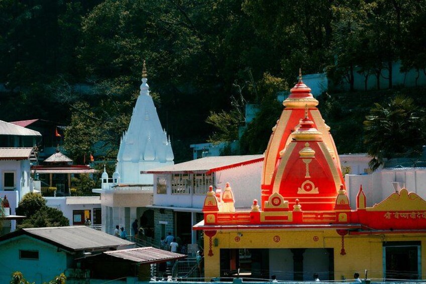 A temple with a red and white spire, surrounded by residential buildings and greenery. 1