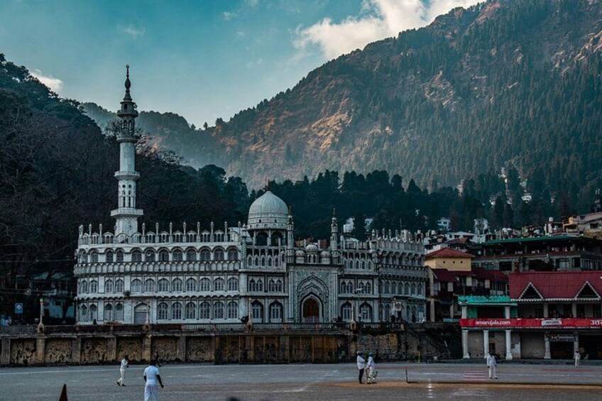 A large, ornate building with a minaret and dome, surrounded by mountains. 2