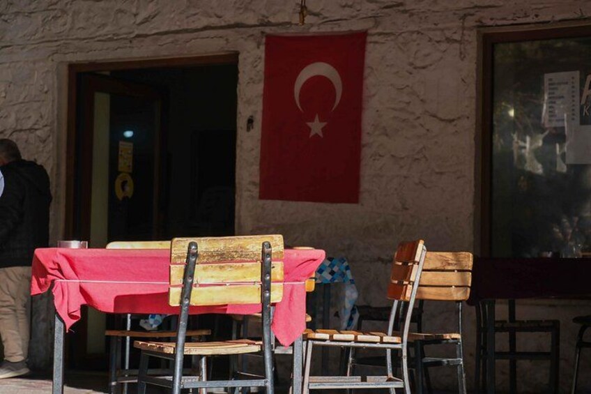 Een tafel met een rode tafelkleed, houten stoelen en een Turkse vlag aan de muur. 2