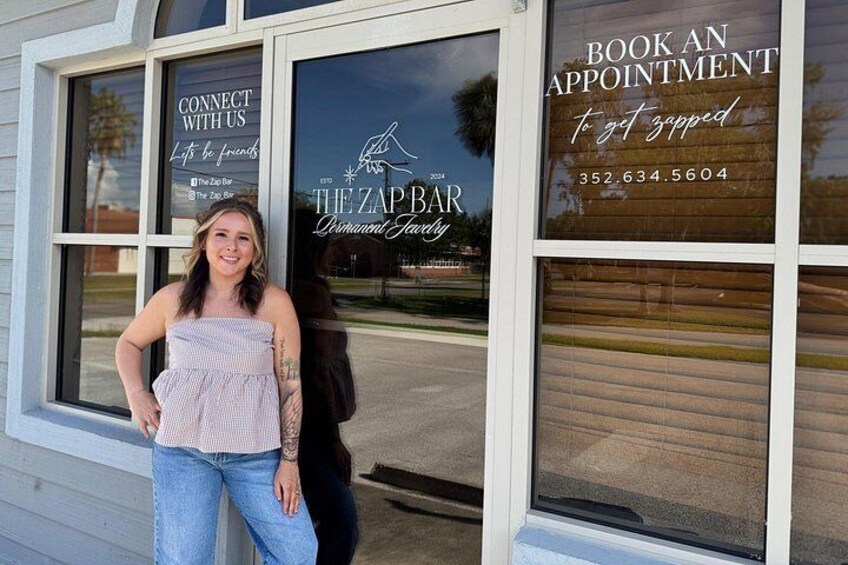 Une femme se tient devant un bâtiment. Une fenêtre affiche l'inscription « PRISE DE RENDEZ-VOUS » et un numéro de téléphone. 3