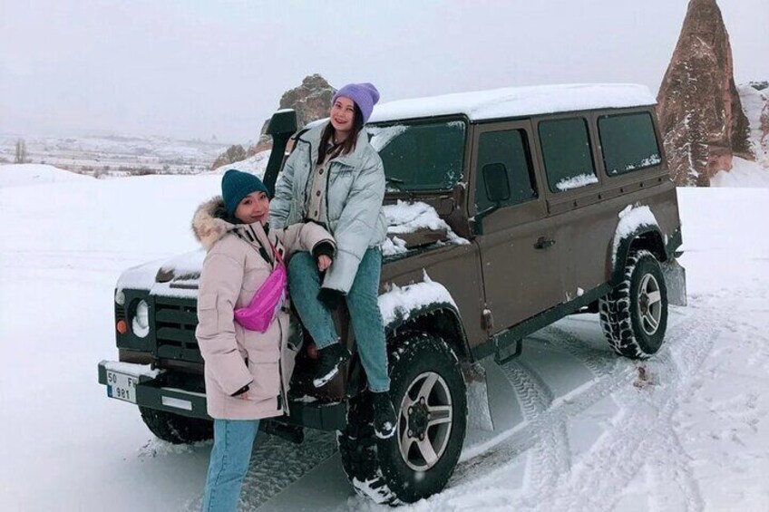 Un SUV marrón estacionado en una carretera nevada con tres personas a su lado. 5