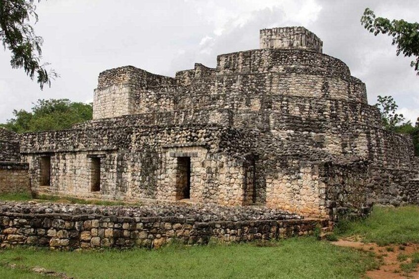 Un'imponente struttura antica in pietra, con più livelli e una torre centrale, circondata da un basso muro in pietra. 2