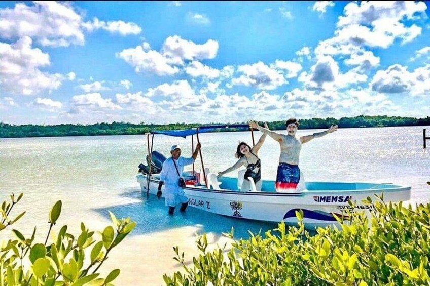 A boat on calm water with people standing on it, surrounded by greenery and a clear sky. 4