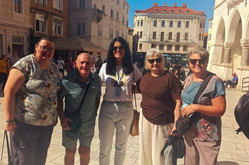 A group of people standing in a public square with historic buildings in the background. 2