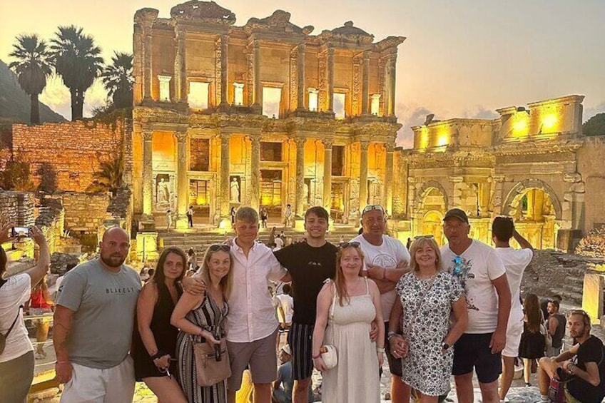 A group of people posing in front of an ancient ruin with columns and arches. 3