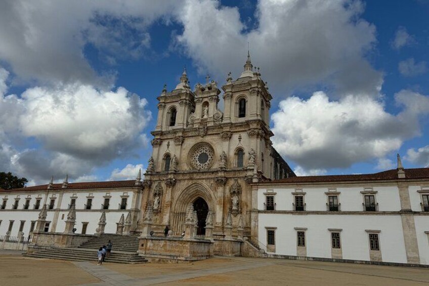 A historic church with a large central archway, flanked by two bell towers, and a courtyard with steps leading to the entrance. 3