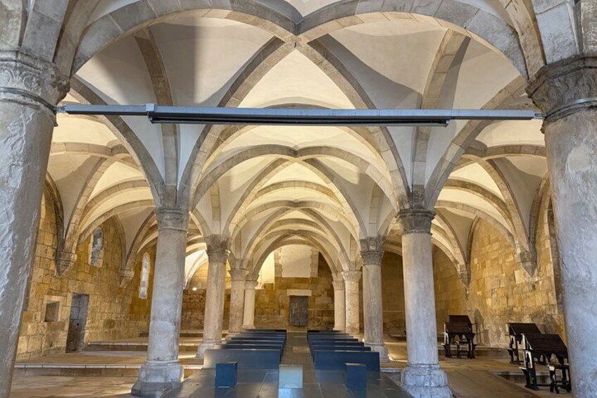 An interior with stone arches, columns, and benches. 4