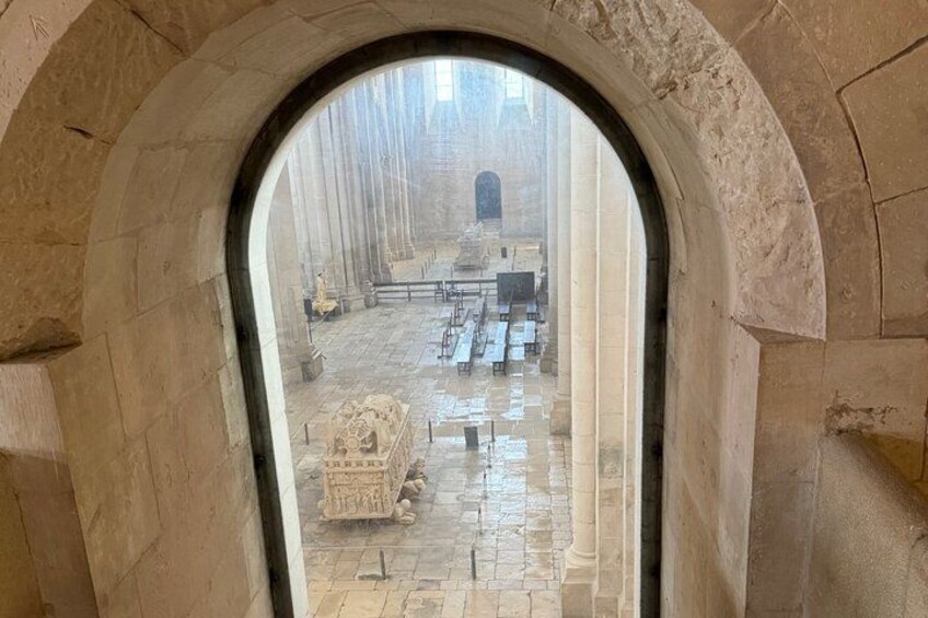 An arched stone doorway leading to a courtyard with stone benches and a central sculpture. 5