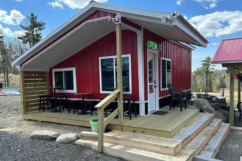 Un bâtiment rouge avec une terrasse en bois et une enseigne verte indiquant « OUVERT ». 1