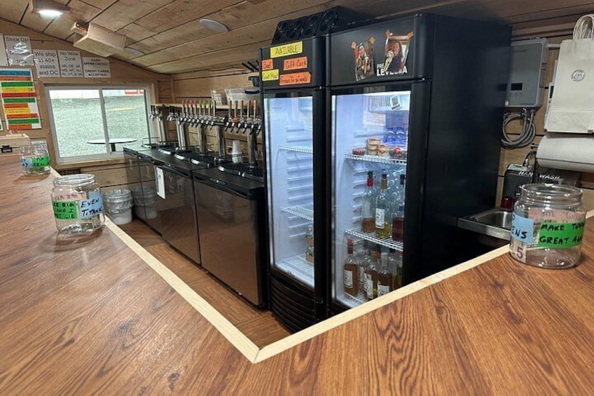 Un distributeur de boissons proposant plusieurs choix, un réfrigérateur rempli de boissons et un comptoir en bois. 2