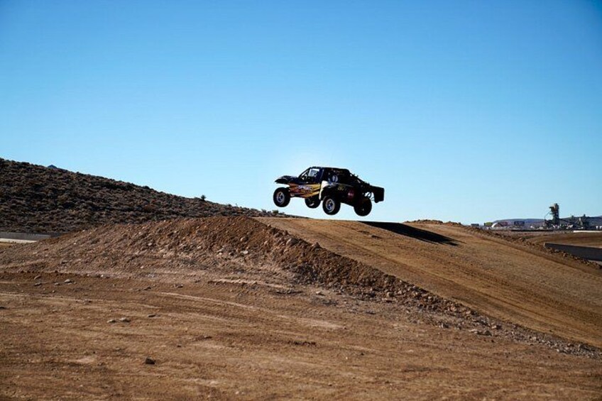A quad bike in mid-air over a dirt ramp. 4