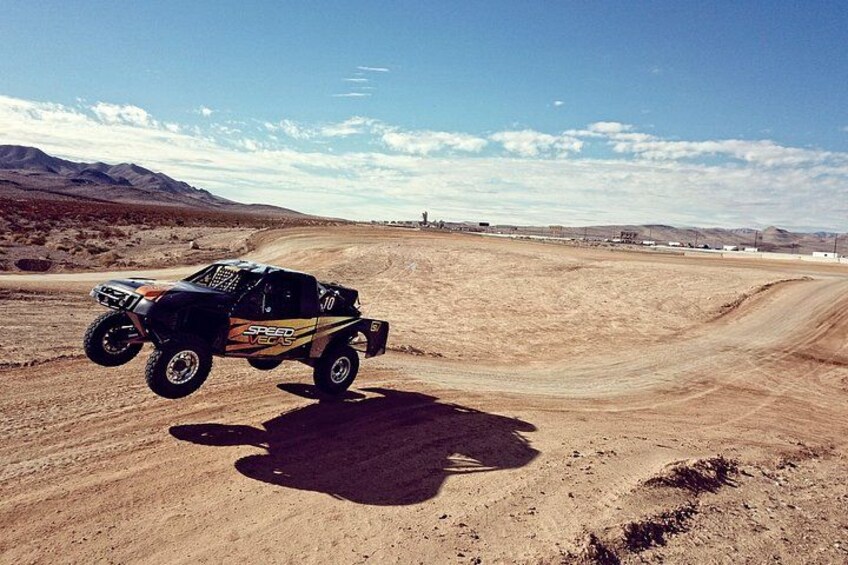 A vehicle on a dirt road in a desert landscape. 2