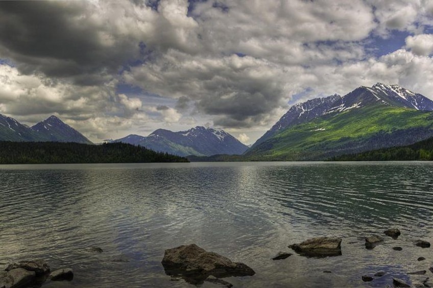 A lake surrounded by mountains with snow-capped peaks and a cloudy sky. 3