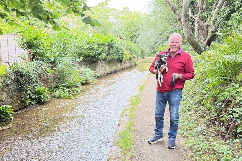A person holding a dog on a narrow path surrounded by greenery. 2